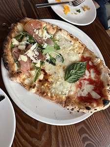 Margherita pizza with basil, cheese, and tomato sauce on a wood table.