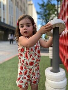 Young girl playing with a large outdoor game in a city park.