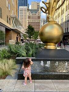 City sculpture fountain with child, urban outdoor art, downtown skyline, public art installation.