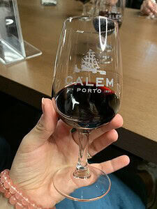 Hand holding a Calem Porto wine glass with red wine inside.