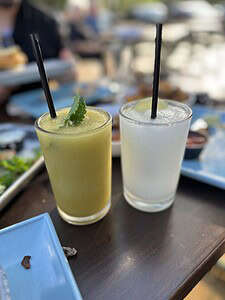 Two refreshing fruit smoothies, one green and one white, on a restaurant table.