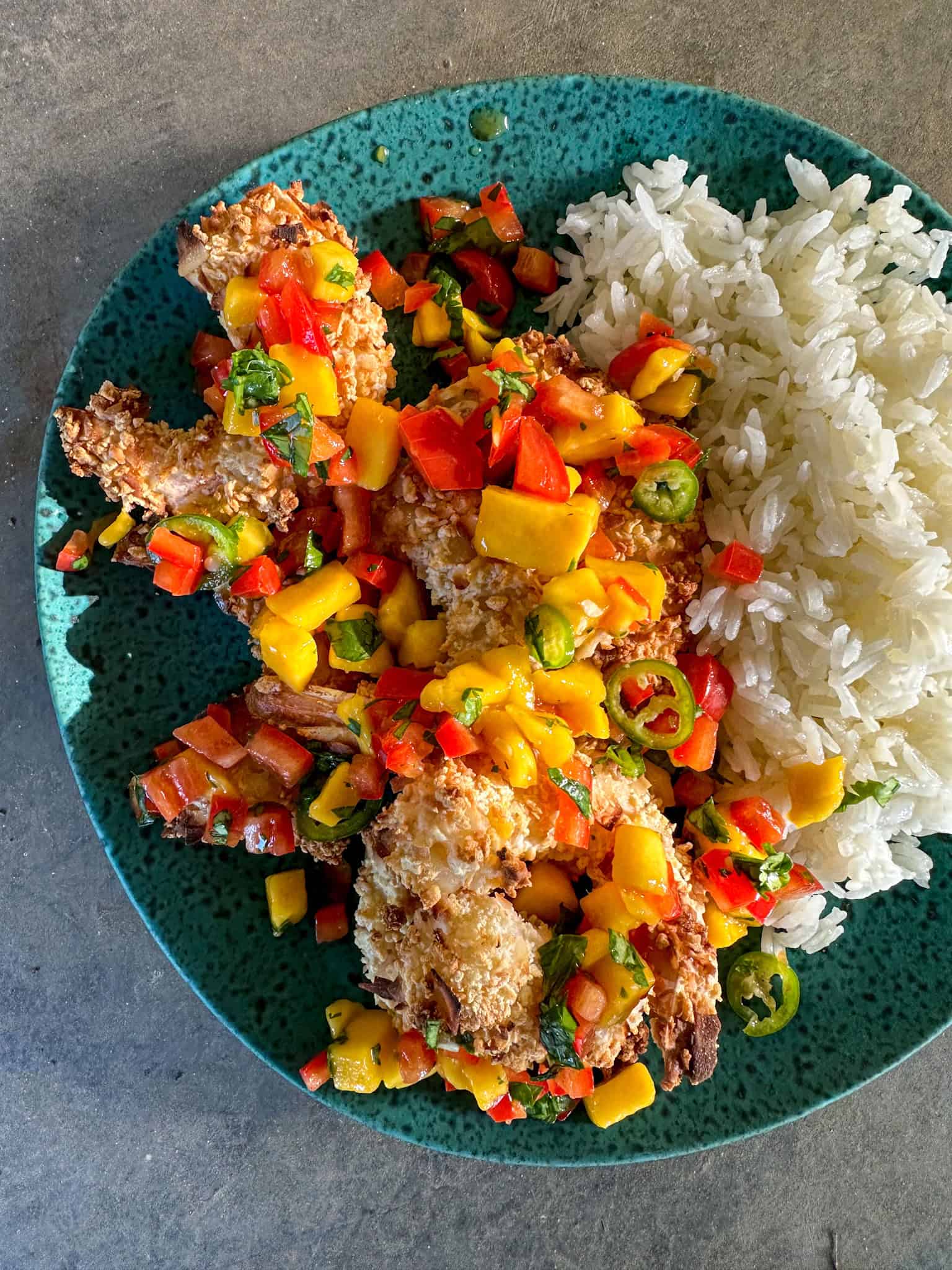 Delicious coconut shrimp served with fresh mango salsa on a vibrant blue plate. Perfect for a tropic.